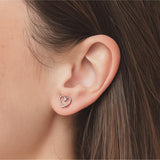 Heart-shaped earring worn by a woman with brown hair.