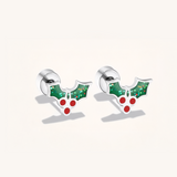 Silver earrings with green holly leaves and red berries on a light background