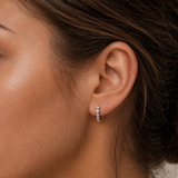 Close-up of model wearing Silver Mini Bezel Heart Huggie Earrings with clear cubic zirconia stones set in delicate heart-shaped bezels