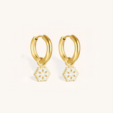 Gold hoop earrings with snowflake charms on a background.