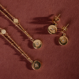 Gold necklace and earrings on a red textured background