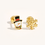 A gold Christmas set with snowflake and snowman earrings on a beige background.