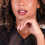 Close-up of a woman with curly hair wearing pink lipstick and gold jewelry.