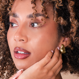 Woman wearing a gold molten hoop earring with a close-up of the earring.
