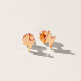 Rose gold lightning bolt earrings on a light beige background