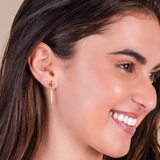 Close-up of a woman wearing gold earrings with a neutral background