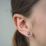 Close-up of a girl wearing a panda-shaped earring with a pink bow.