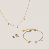 Gold necklace, bracelet, and earrings on a beige background