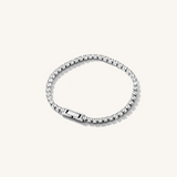 A silver cubic zirconia tennis bracelet on a beige background.