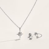 Silver necklace with star pendant, earrings, and ring on a light gray background