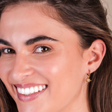 Close-up of a woman wearing a gold star-shaped earring with a blurred background.