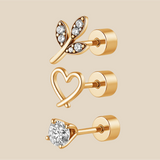 Set of gold earrings with heart, leaf, and round designs on a beige background