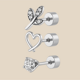 Set of silver earrings with heart, leaf, and round designs on a beige background