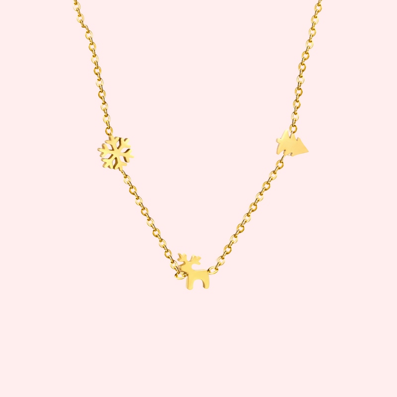 Gold necklace with Christmas charms on a light pink background.