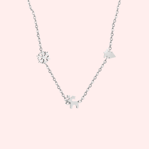 Silver necklace with Christmas charms on a light pink background.