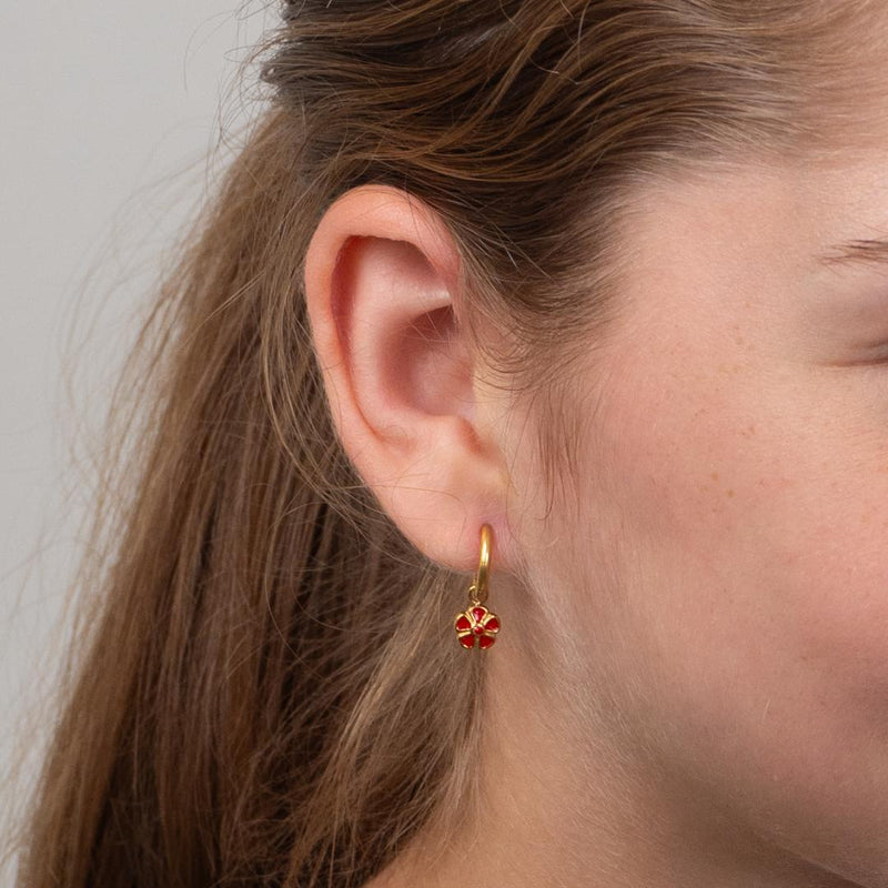 Close-up of a girl wearing a gold daisy hooped earring.