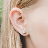 Close-up of a girl wearing a daisy flower earring.