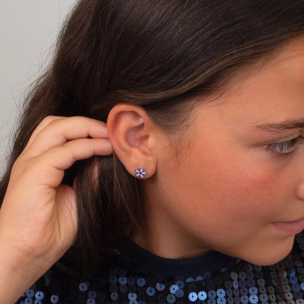 Close-up of a young girl wearing a floral earring with a neutral background