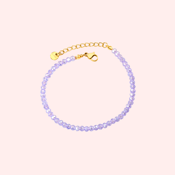 Lavender beaded bracelet with gold clasp on a light pink background