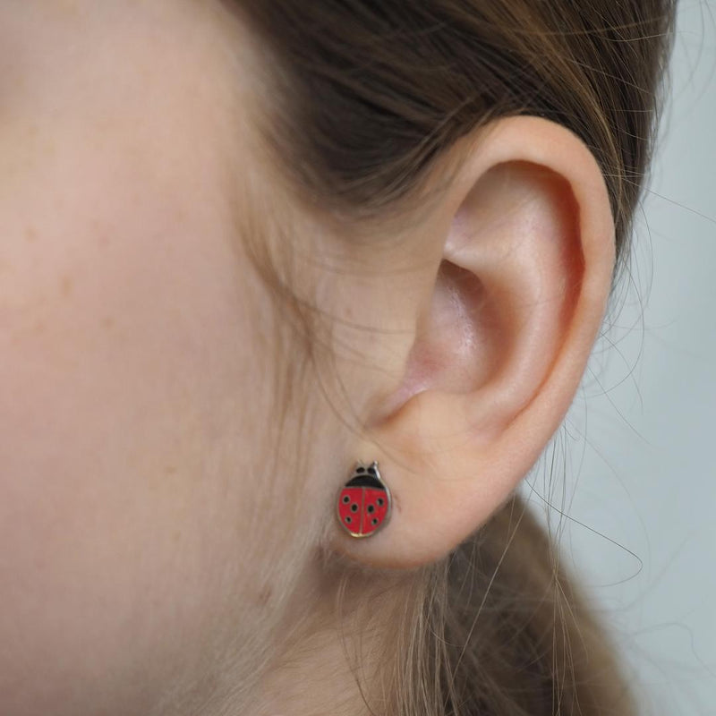 Close-up of a girl wearing a ladybug earring with a plain background