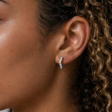 Close-up of model wearing Silver Wave Crystal Huggie Earrings with a curved wave design set with clear cubic zirconia stones