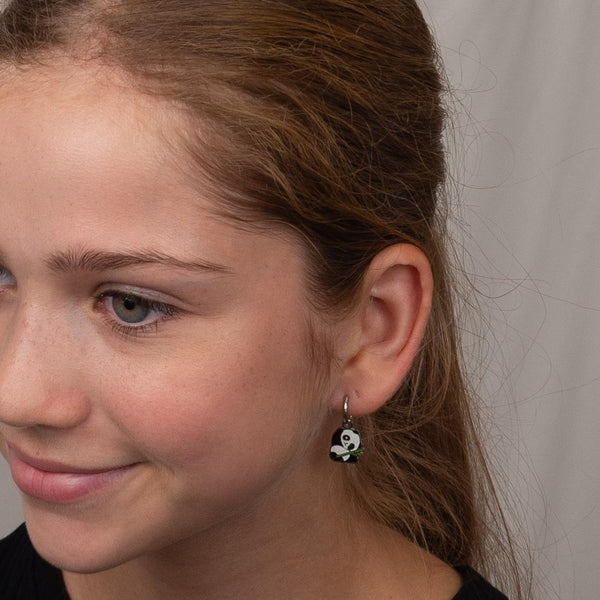 Close-up of a girl wearing silver panda hooped earrings.