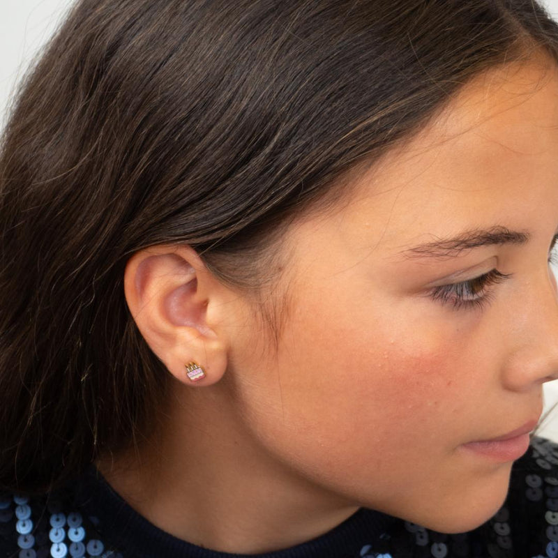 Close-up of a girl wearing cake flat back earrings with a neutral background.