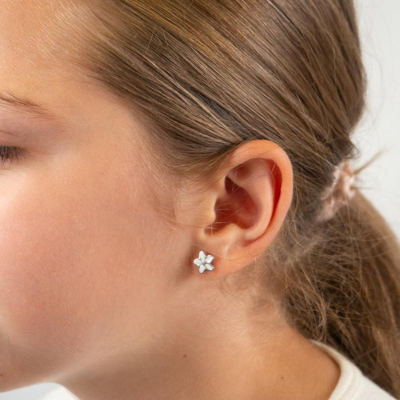 Close-up of an ear wearing a floral earring with blurred background