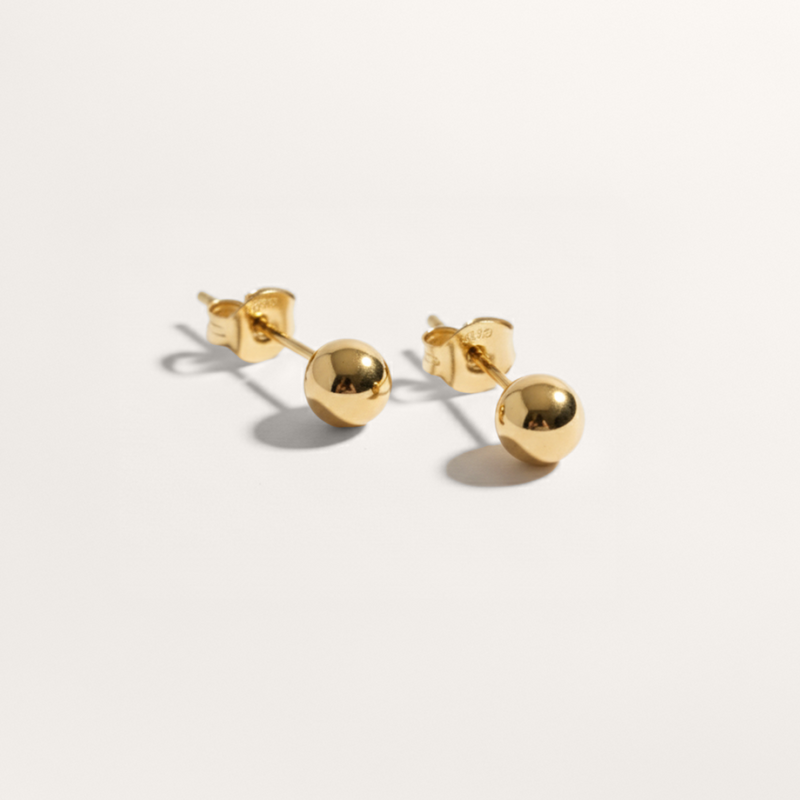 Ball hypoallergenic stud earrings in gold on white background
