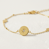 Gold bracelet with a round pendant featuring a star design on a light background