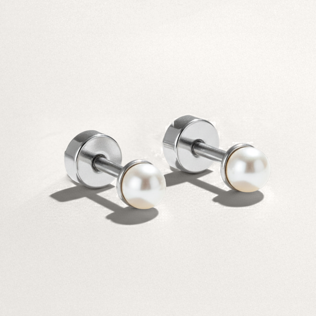 Pair of silver earrings with pearl-like beads on a light gray background