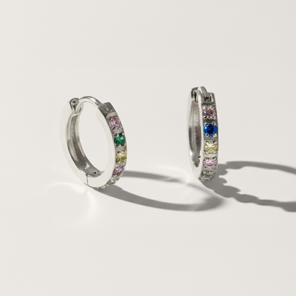 Colourful cubic zirconia hypoallergenic huggie earring in silver on white background
