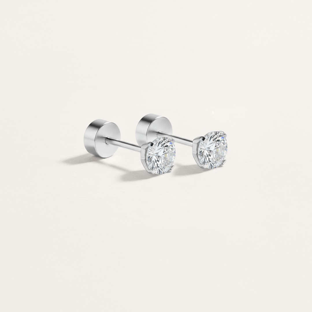 Pair of silver stud earrings with clear gemstones on a light gray background