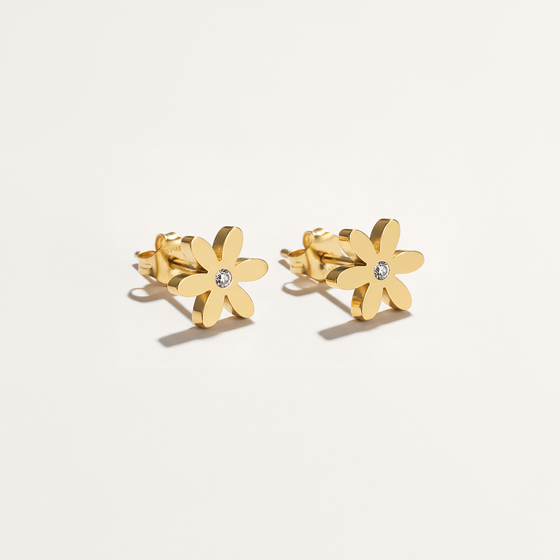 Gold flower-shaped earrings on a light beige background