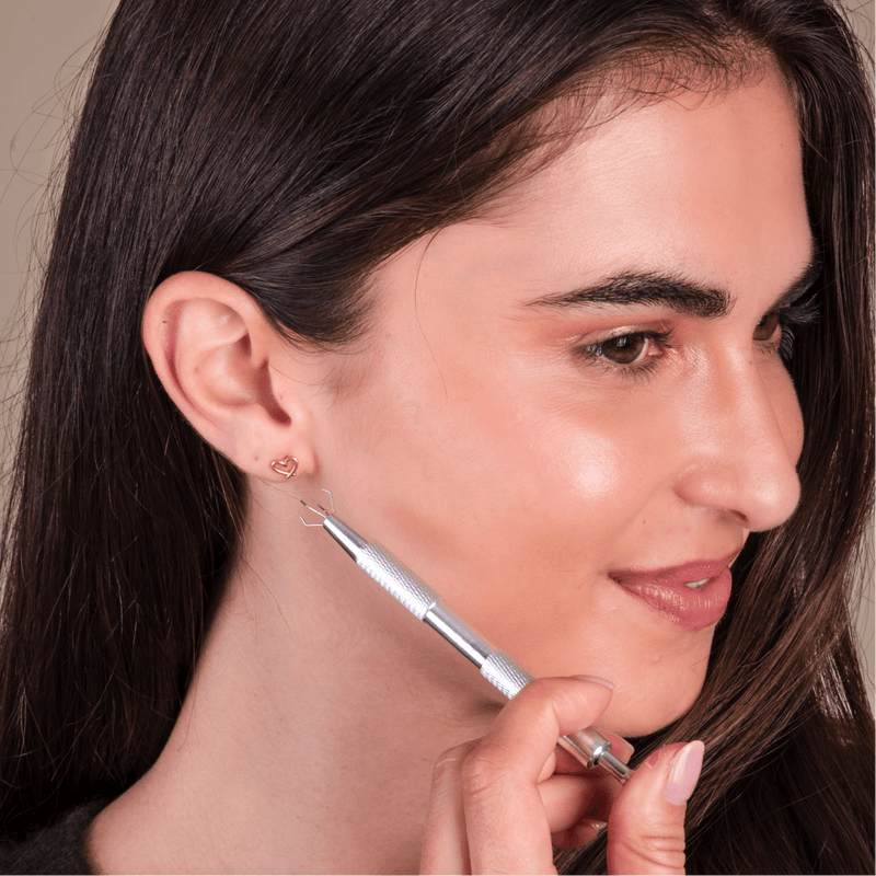 A girl using the earring grabber tool to help with earring application.