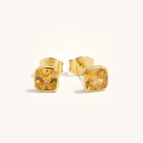 Gold stud earrings with yellow gemstones on a white background
