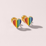 Heart-shaped earrings with rainbow design on a light pink background