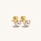 Pair of gold earrings with pearl-like stones on a light gray background.