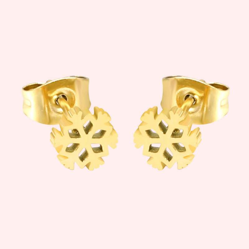 A pair of gold snowflake stud earrings on a light pink background.