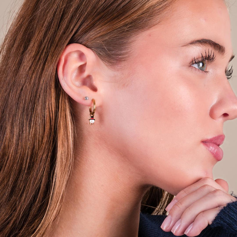 Girl wearing snowman gold hoops against a white background.