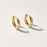 Hammered hypoallergenic huggie earring in gold on white background
