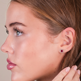 Close-up of a woman wearing a red square earring on a neutral background