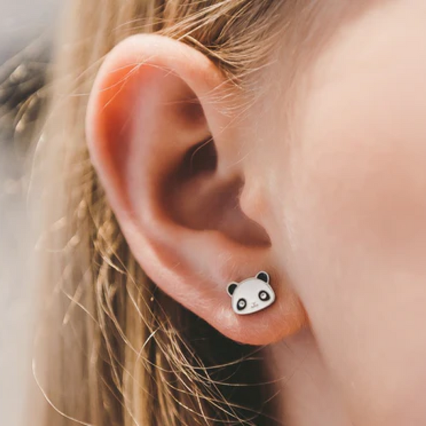 Panda-shaped earrings worn on an ear with a blurred background
