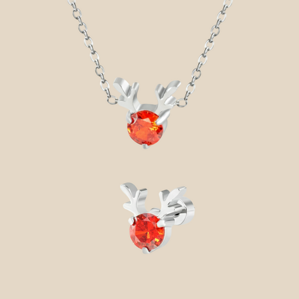 A Christmas set featuring a silver Rudolph charm necklace and earrings on a beige background.