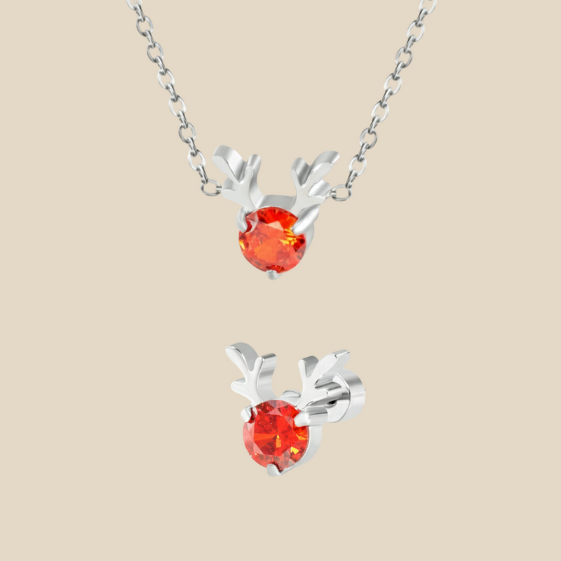 A Christmas set featuring a silver Rudolph charm necklace and earrings on a beige background.