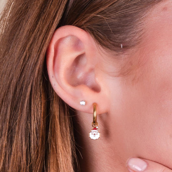 A closeup of a girl wearing santa charm gold hoop earrings.