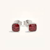 Silver stud earrings with red gemstones on a white background