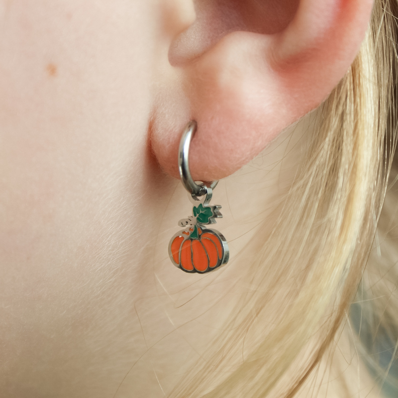 Silver earring with a pumpkin charm worn by a girl.