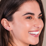 Close-up of a woman wearing gold earrings with a neutral background